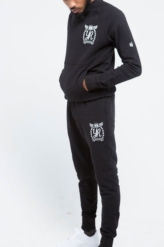 Yung'n'Rich black crew neck tracksuit detail shot on male model, highlighting white ornate logo branding and pocket details, close-up view of fabric texture and fit, photographed against white background